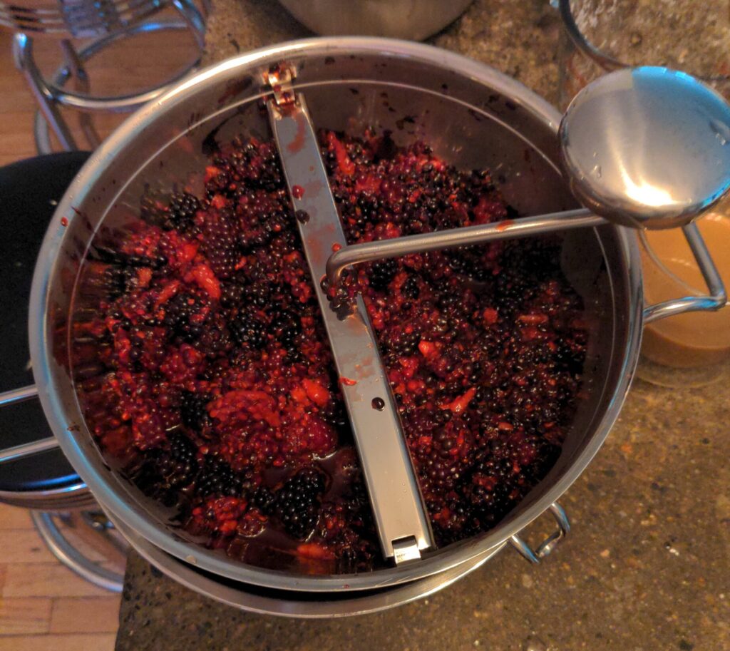 Blackberries in a food mill to remove the seeds.